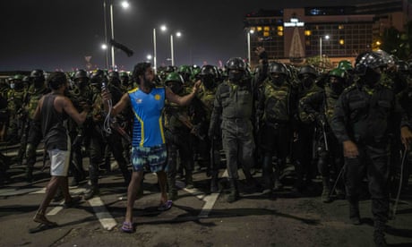 A demonstrator shouts slogans as Sri Lankan soldiers arrive to remove people from a protest camp outside the president’s office in Colombo early on Friday