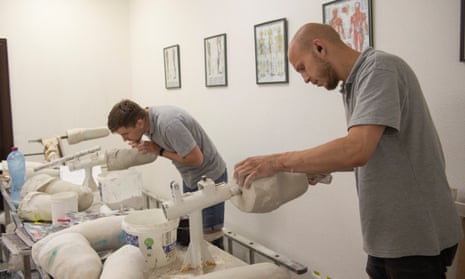 Usevol (R), a specialist at the clinic, and Misha, a former soldier who lost a leg in the war, adjust molds for creating prosthetics.