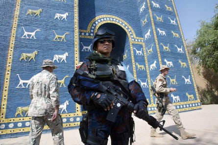 Philippine military police stand guard at the Ishtar gate as Polish and US soldiers pass by.