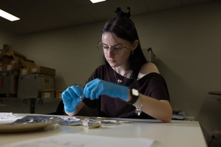 Archaeology student Emily Totivan examines artefacts, wearing blue gloves