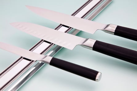 Three kitchen knives lie flat against a magnetic knife rack