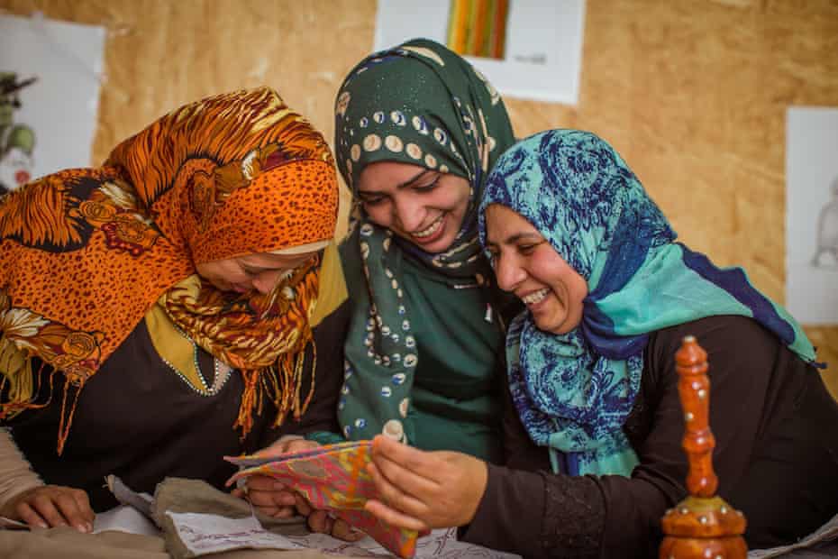 Female refugees looking at embroidery