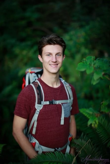 Portrait of a young man wearing a hiking backpack against a background of foliage.