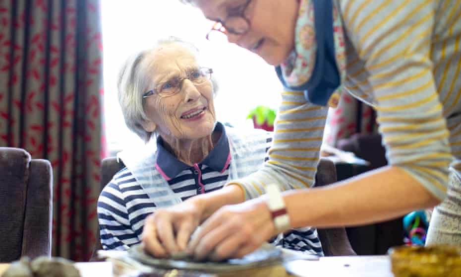 A care home resident is guided with her clay modelling.