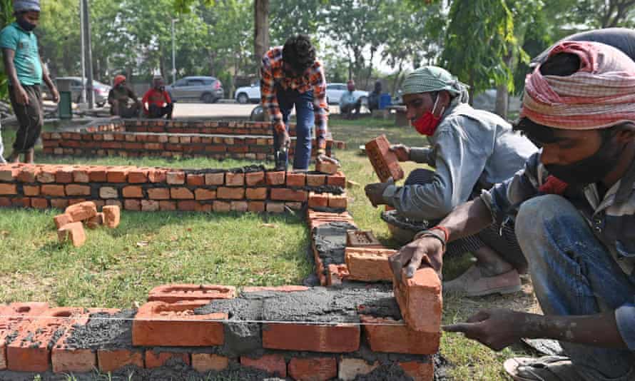 Workers are seen constructing makeshift platforms for funeral pyres in a park inside the premises of a crematorium in Delhi