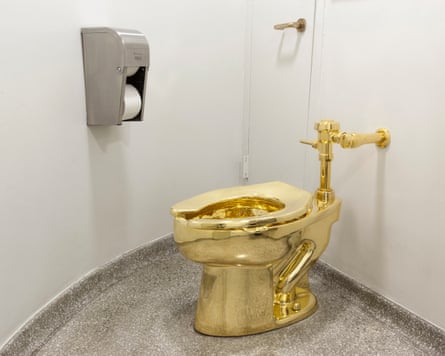 A solid gold toilet in a bathroom with a toilet roll dispenser on the wall.