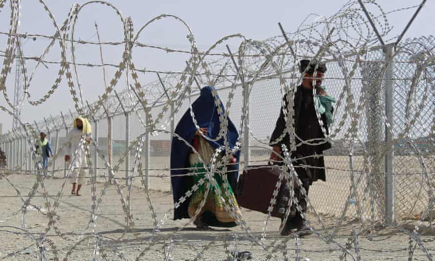 Afghans walk along a fenced corridor after crossing into Pakistan near Chaman on Saturday.