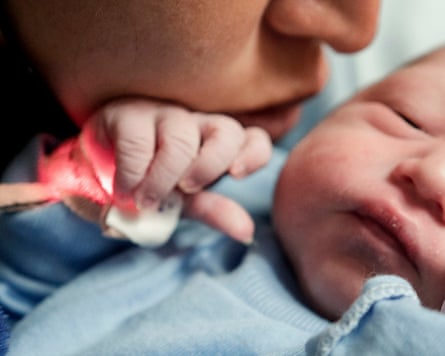 Close up of a woman’s face next to a new born baby
