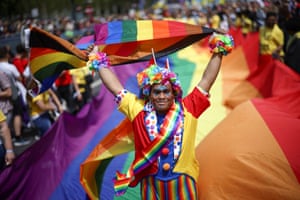 A person holds up a Pride flag as they walk along a giant Pride flag