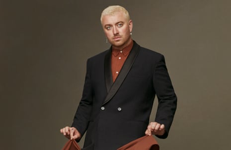 Sam smith looking serious while lifting the hem of his long jacket