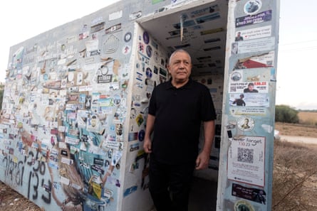 Gadi Eisenkot stands in a doorway of a bomb shelter wall covered with memorial stickers.