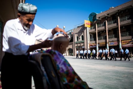Police walking past a barber in the old town of Kashgar in Xinjiang, China in June 2017