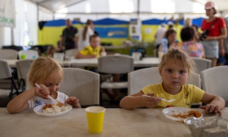 Ulyana Pidlesina and her sister Solomua eat as they wait to be transferred to other parts of the country, in Zaporizhzhia.