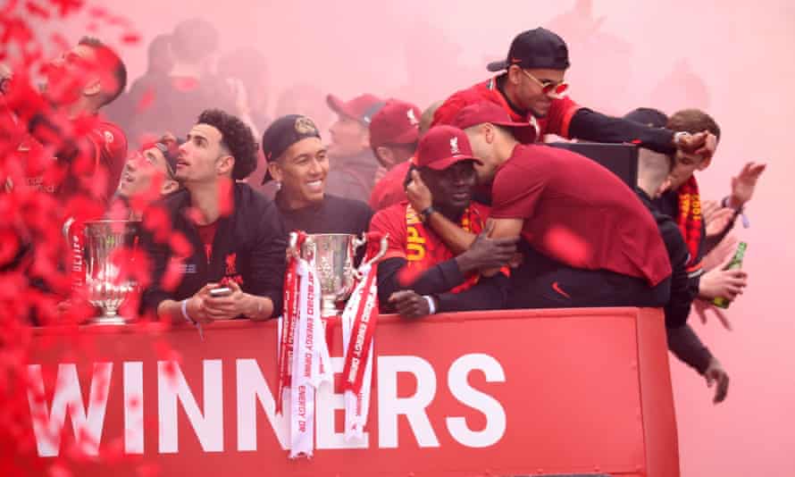 Liverpool’s Curtis Jones, Roberto Firmino, Sadio Mané and teammates celebrate alongside the FA and Carabao Cup trophies