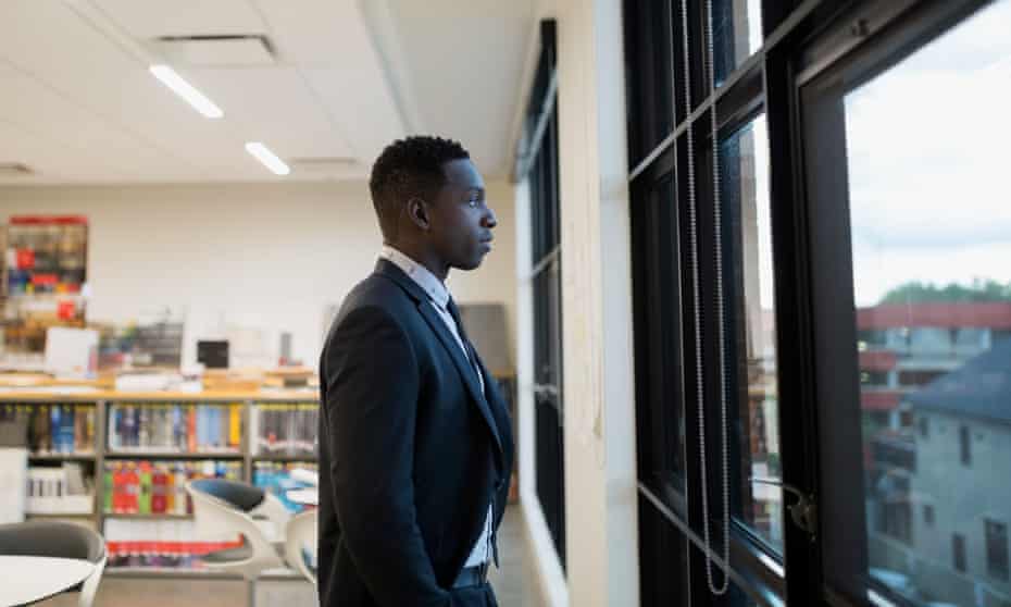 Black man in suit looking out a window