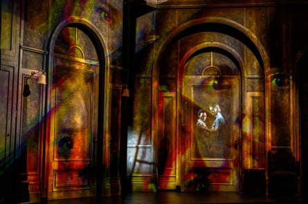 Theo and Luke embrace in a doorway amid colourful lighting on the Haunting of Hill House set