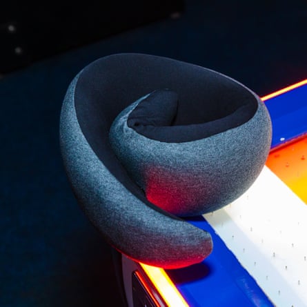 A grey and black Ostrichpillow Go neck pillow on an arcade game machine