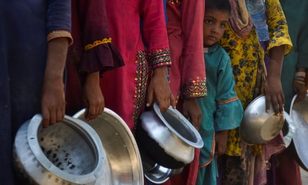 After severe floods in Sehwan, Pakistan, people displaced by the floods gather at a camp to receive food aid.