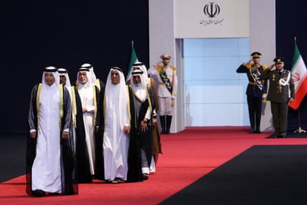Members of the Qatari delegation, dressed in robes, walk along a red carpet