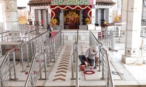 A man paints circles on the floor of a temple in New Delhi for devotees to maintain social distancing as the government plans to open places of worship as part of the easing of the nationwide Covid-19 lockdown.