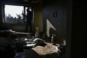A police officer holding a gun in a room strewn with debris