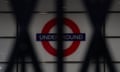 London Underground sign with closed metal shutters in front of it.