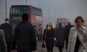 Commuters and traffic crossing London Bridge on a smoggy morning.