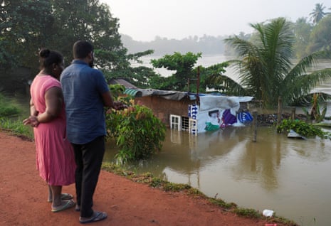People look towards a house partially submersed by flooding in Peliyagoda, Sri Lanka.