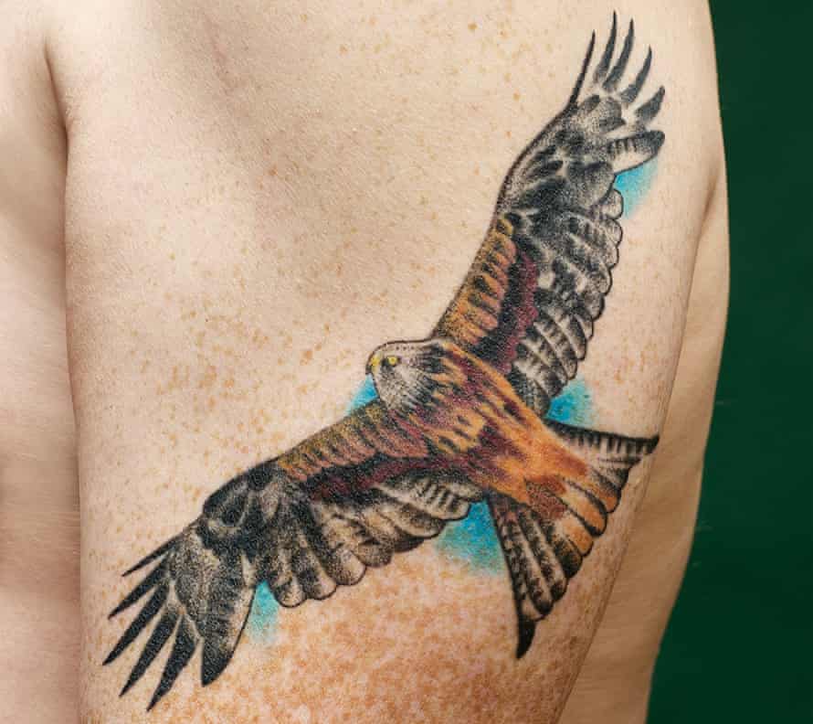 A man's bare arm showing a red kite tattoo