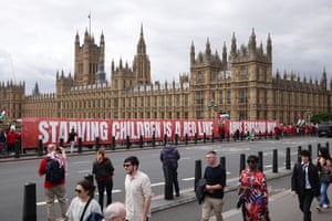 people walk in front of a banner reading 'starving children is a red line'