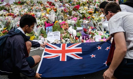 NZEALAND-ATTACK-MOSQUEStudents display the New Zealand national flag next to flowers during a vigil in Christchurch on March 18, 2019, three days after a shooting incident at two mosques in the city that claimed the lives of 50 Muslim worshippers. - New Zealand will tighten gun laws in the wake of its worst modern-day massacre, the government said on March 18, as it emerged that the white supremacist accused of carrying out the killings at two mosques will represent himself in court. (Photo by ANTHONY WALLACE / AFP)ANTHONY WALLACE/AFP/Getty Images