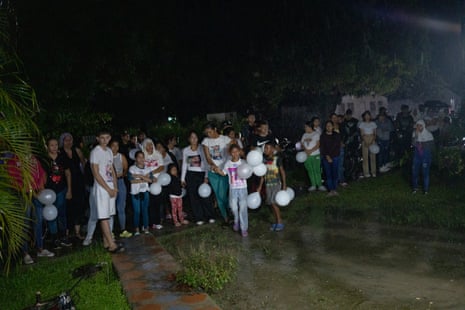 Neighbours stand in the rain in front of the Guedez García family home after their return to Poblado Uno
