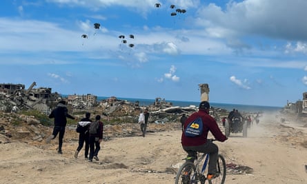 Palestinians rush towards the beach to collect aid dropped by an aeroplane