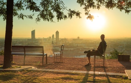 A man sitting in a chair enjoys a sunrise over Lyon