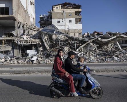 A family on a motorbike pass by the ruins of a building destroyed by an Israeli strike on Tyre, southern Lebanon.