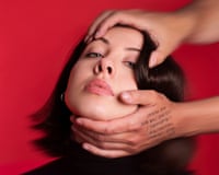 Performance artist Harriet Richardson's face is gripped and tilted back by two hands against red