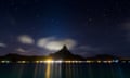 Mountain Otemanu in Bora Bora, French Polynesia. There are many colored artificial lights in the shore reflecting in the flat calm sea water.