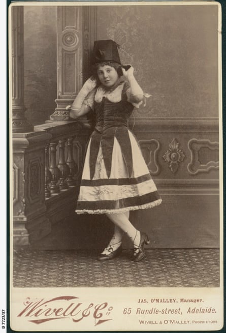A young girl in black and white photo, wearing a layered dress with a costume telephone on her head