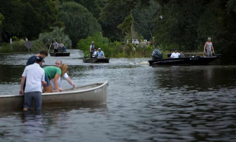 People use boats to access a neighborhood after flooding August 16, 2016