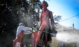 A worker cleans with a high pressure water jet red paint on the statue of Swiss banker, merchant and philanthropist David de Pury in Neuchatel.
