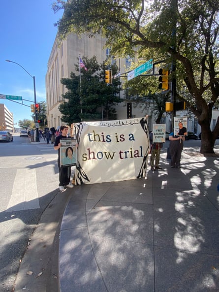 People holding a sign that says 'this is a show trial'