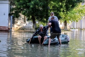 People help an elderly man to get in an inflatable boat as he evacuates from his home. A number of settlements were completely or partially flooded, the Kherson regional governor Oleksandr Prokudin said.