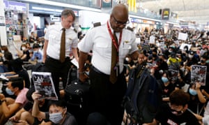 Airline crew members walk past anti-government protesters during a demonstration at Hong Kong airport.