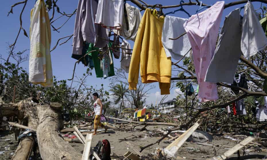 A woman passes drying clothes on a line amid the debris left by Typhoon