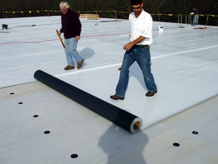 people rolling out roofing material