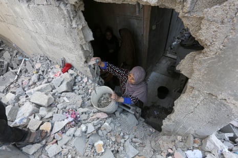 A woman clears rubble from the wall of a destroyed building after an attack on the Gaza town of Deir al-Balah on the last day of Eid al-Fitr.