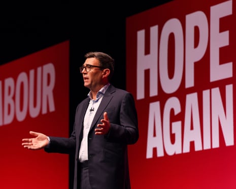 Andy Burnham opens his arms as he speaks in front of a Labour sign and a sign saying 'Hope again'