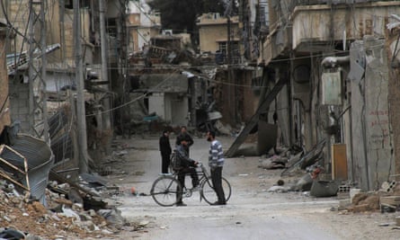 Men chat near damaged buildings in Daraya, near Damascus, in 2014