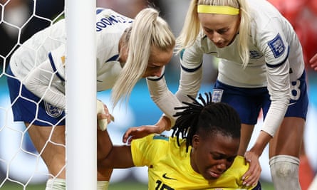 Chiamaka Nnadozie of Nigeria, on the ground, with England’s Chloe Kelly and Alex Greenwood holding her arm and shoulder