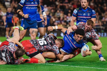 Emre Guler of Wakefield is tackled by Jack Hughes and Nathan Wilde of Leigh